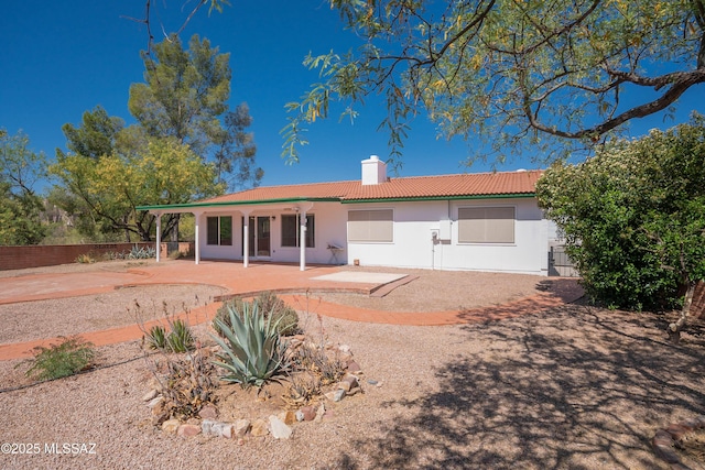 back of house with fence, a patio, stucco siding, a chimney, and a tile roof