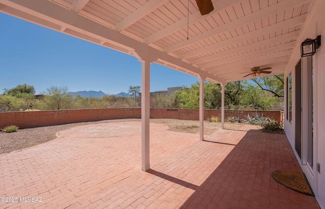 view of patio with a fenced backyard, a ceiling fan, and a mountain view