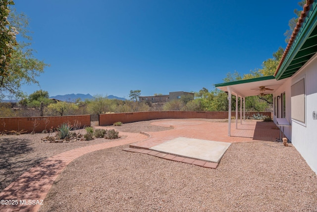view of yard featuring a patio, ceiling fan, a mountain view, and a fenced backyard