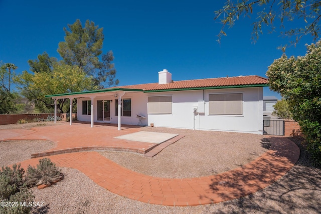 back of property with fence, a patio, stucco siding, a chimney, and a tiled roof