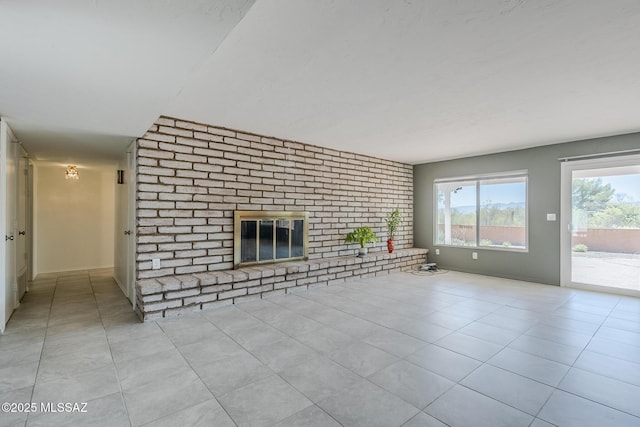 unfurnished living room featuring tile patterned flooring, a fireplace, and brick wall