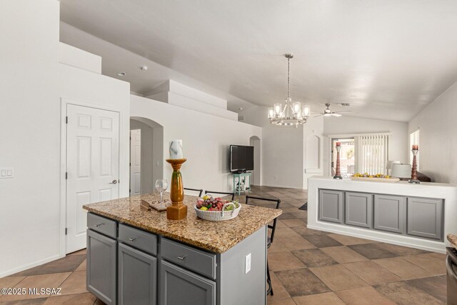 kitchen featuring arched walkways, gray cabinets, a center island, open floor plan, and lofted ceiling