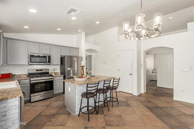kitchen with visible vents, a center island, arched walkways, gray cabinetry, and stainless steel appliances