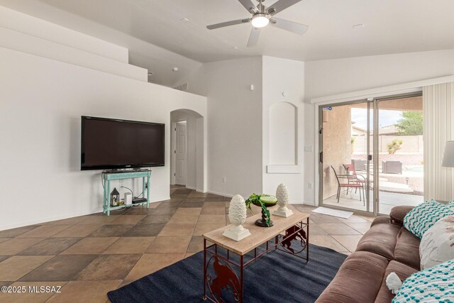 living area featuring arched walkways, baseboards, a ceiling fan, and high vaulted ceiling
