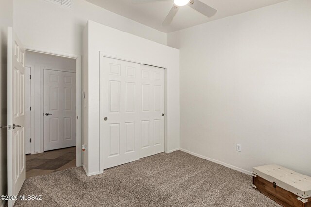 unfurnished bedroom featuring carpet floors, baseboards, ceiling fan, and a closet