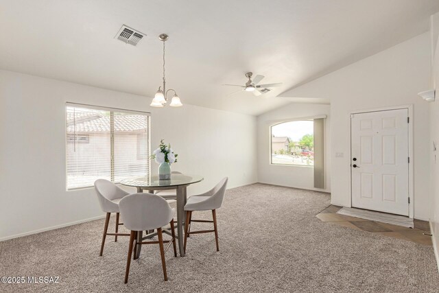 dining area featuring visible vents, ceiling fan with notable chandelier, lofted ceiling, and light colored carpet