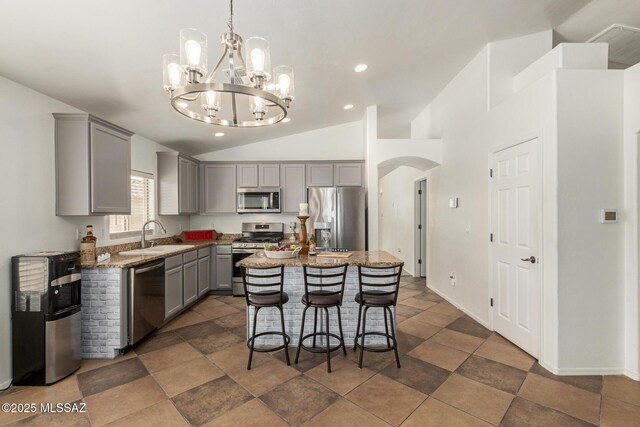 kitchen with a sink, stainless steel appliances, lofted ceiling, a kitchen island, and gray cabinetry
