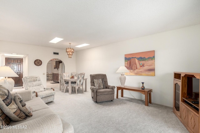 living room with arched walkways, visible vents, and light carpet