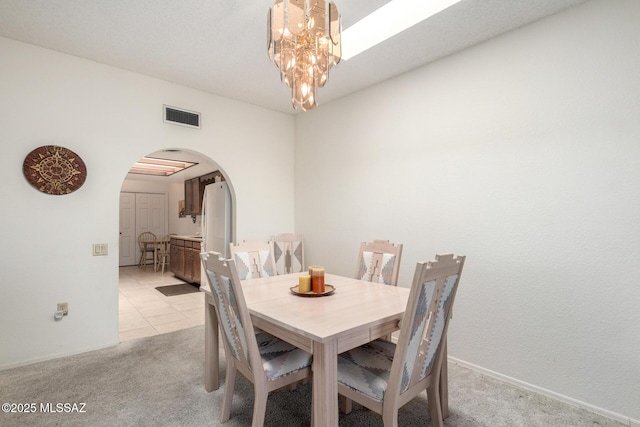 dining area featuring arched walkways, an inviting chandelier, light colored carpet, baseboards, and visible vents