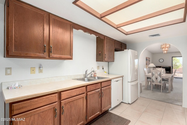 kitchen featuring a sink, visible vents, light carpet, arched walkways, and dishwasher