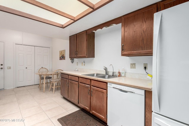 kitchen with light tile patterned floors, white appliances, light countertops, and a sink