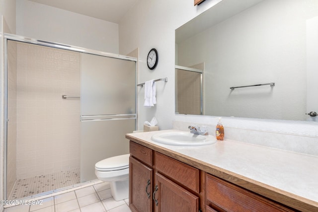 bathroom featuring tile patterned floors, toilet, vanity, and a shower stall