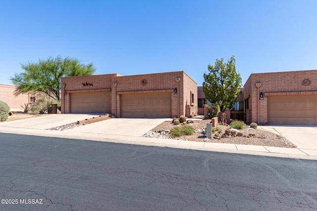 southwest-style home with concrete driveway, a garage, and brick siding