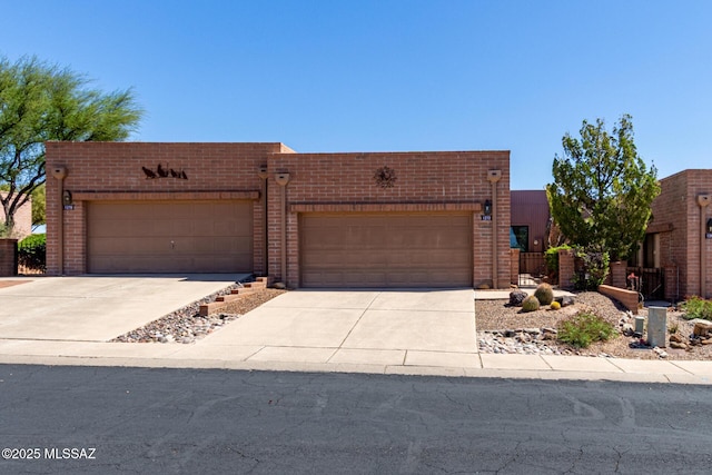 adobe home featuring fence, concrete driveway, brick siding, and an attached garage