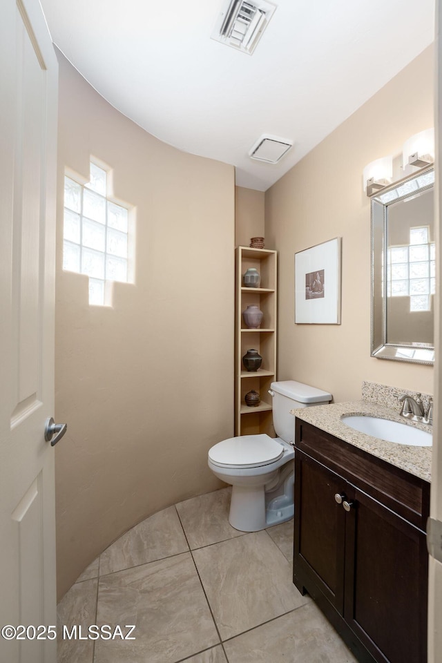 bathroom featuring toilet, visible vents, vanity, and plenty of natural light
