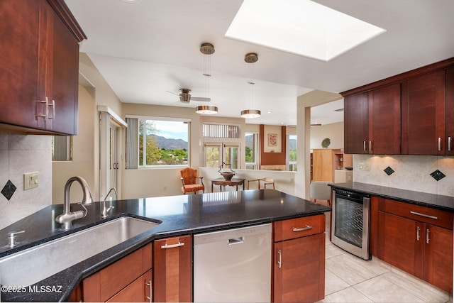 kitchen featuring beverage cooler, stainless steel dishwasher, backsplash, a sink, and a ceiling fan
