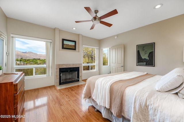bedroom with a fireplace, ceiling fan, recessed lighting, and light wood finished floors