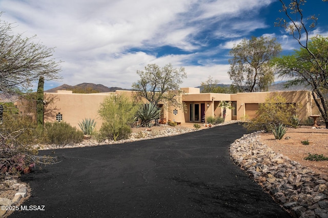 pueblo-style house featuring driveway, a garage, and stucco siding