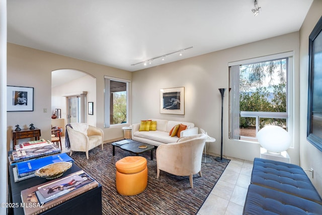living area featuring rail lighting, light tile patterned flooring, and arched walkways