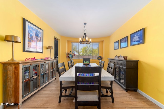 dining area with a chandelier, light wood finished floors, and baseboards