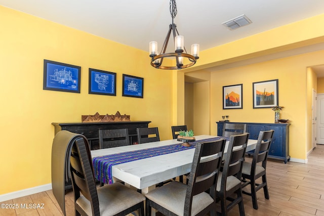 dining space with baseboards, a chandelier, visible vents, and light wood-style flooring