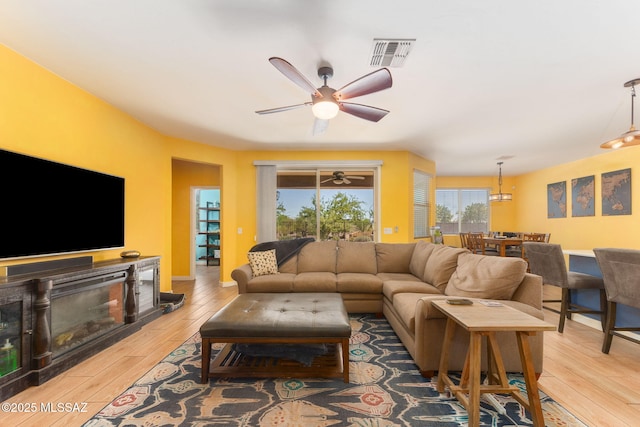 living room with wood finished floors, visible vents, and ceiling fan