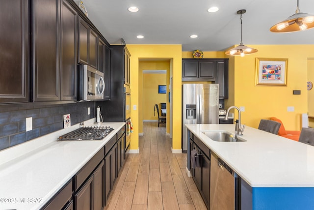 kitchen with light countertops, light wood-type flooring, appliances with stainless steel finishes, and a sink