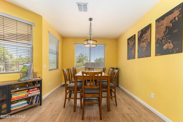 dining room featuring baseboards, light wood-style flooring, and visible vents