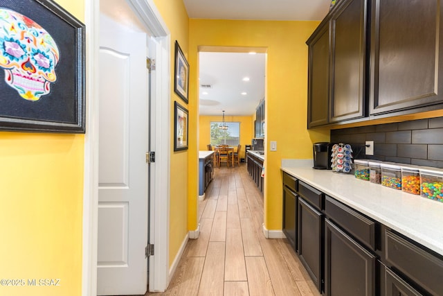 kitchen with light wood-style flooring, baseboards, dark brown cabinetry, backsplash, and light countertops