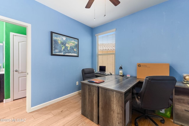 home office featuring light wood finished floors, baseboards, and a ceiling fan