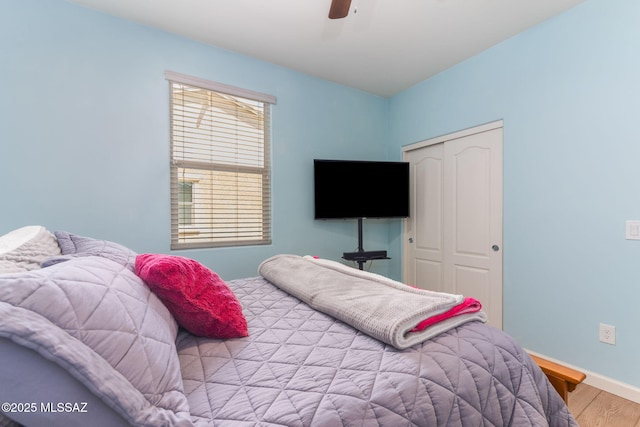 bedroom featuring wood finished floors, a closet, a ceiling fan, and baseboards