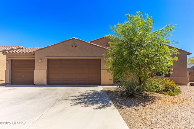 view of front of house with stucco siding, an attached garage, concrete driveway, and a tile roof