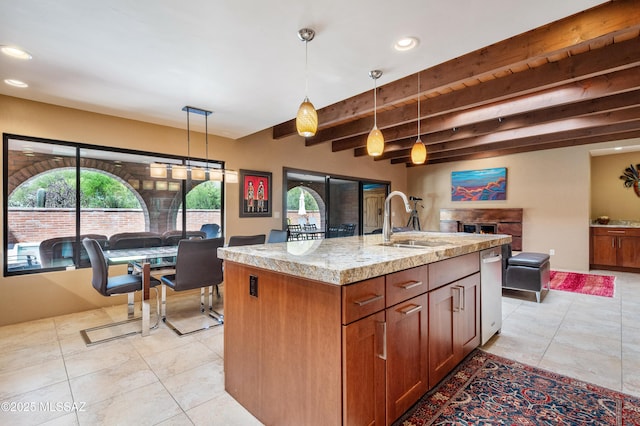 kitchen with a sink, light tile patterned flooring, decorative light fixtures, beam ceiling, and open floor plan
