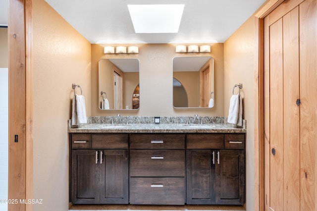 bathroom featuring double vanity, a skylight, and a sink