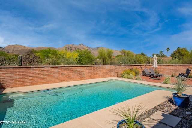 view of swimming pool featuring a patio area, a fenced in pool, and a mountain view