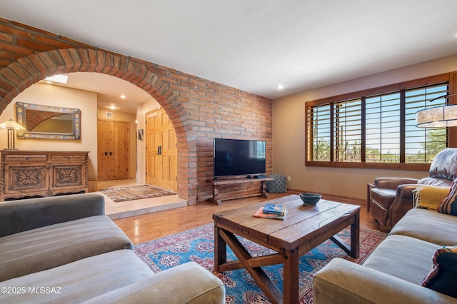 living area with arched walkways, wood finished floors, and recessed lighting
