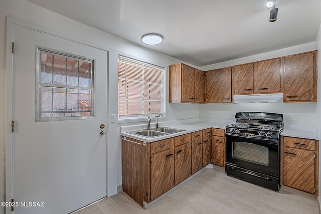 kitchen featuring ventilation hood, black gas range, brown cabinets, and a sink