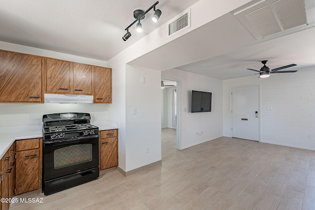 kitchen featuring black gas stove, visible vents, ventilation hood, and brown cabinets
