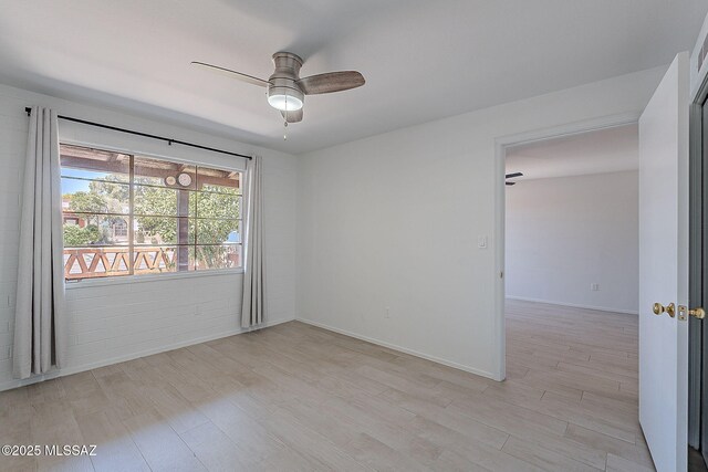 unfurnished room with a ceiling fan, baseboards, and light wood-type flooring