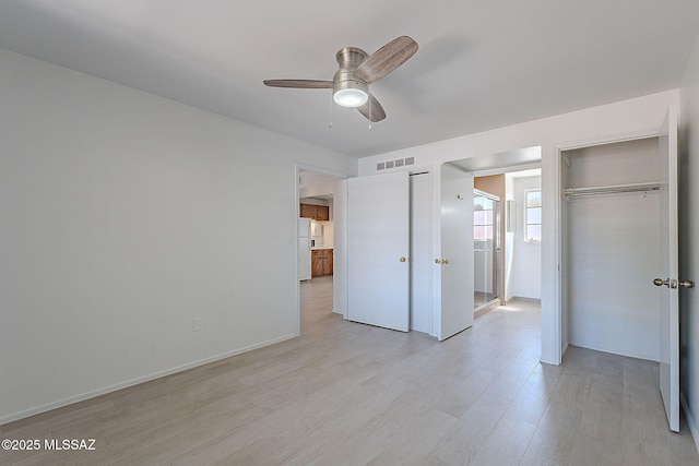 unfurnished bedroom with a ceiling fan, visible vents, freestanding refrigerator, and light wood-type flooring