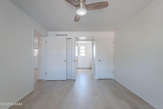 unfurnished room featuring light wood finished floors, a ceiling fan, visible vents, and baseboards