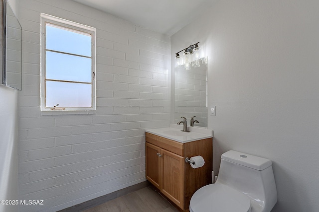 bathroom with toilet, wood finished floors, vanity, and plenty of natural light