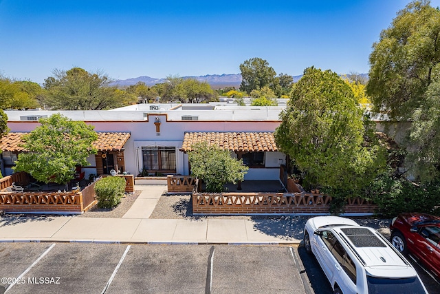 view of front of house with stucco siding, uncovered parking, a mountain view, and a tile roof