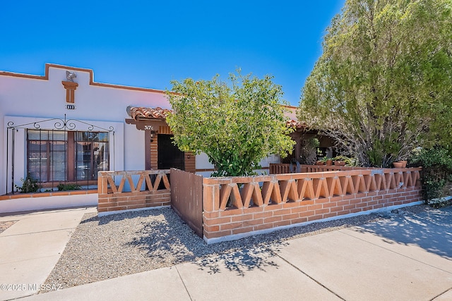 view of front of home with fence, stucco siding, and a tile roof