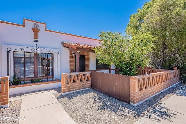 view of front facade with fence and stucco siding