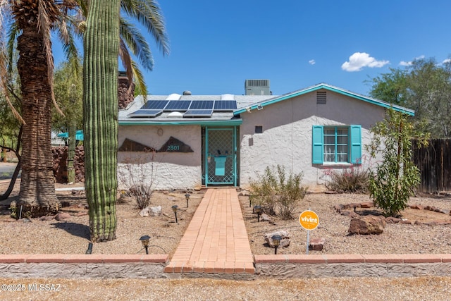 view of front of home featuring stucco siding and roof mounted solar panels