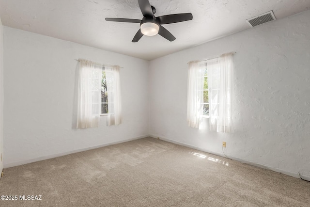 carpeted spare room featuring ceiling fan and baseboards