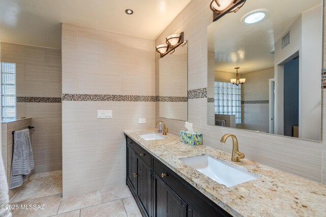 6261 N Placita De Rojelio, Tucson, AZ 85718 - full bath featuring tile walls, double vanity, decorative backsplash, a chandelier, and tile patterned flooring