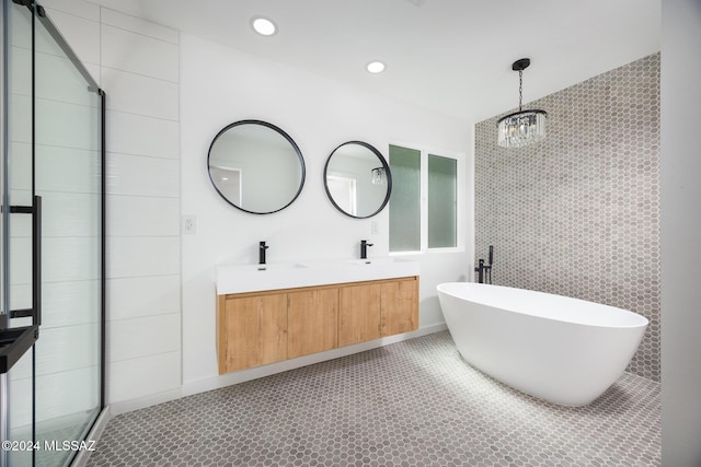 bathroom with a notable chandelier, double vanity, tile walls, a soaking tub, and tiled shower