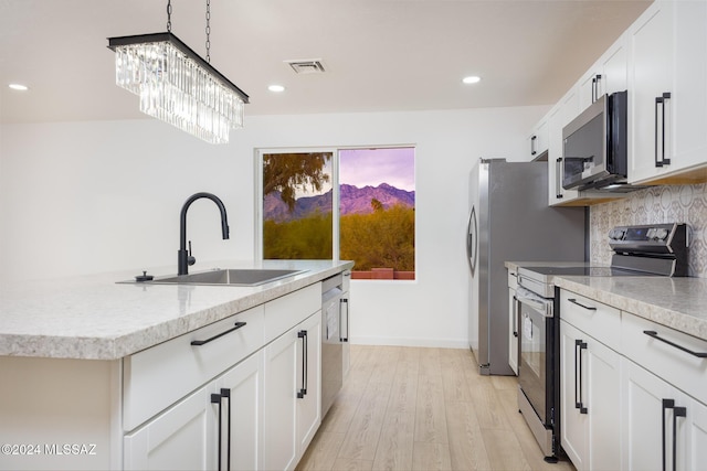 kitchen with decorative backsplash, visible vents, appliances with stainless steel finishes, light wood-type flooring, and a sink